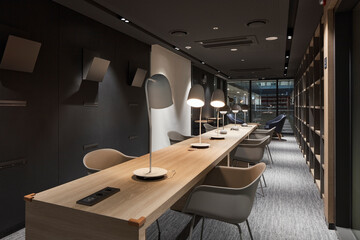Cozy study library with long communal desk and warm task lighting © Namsun