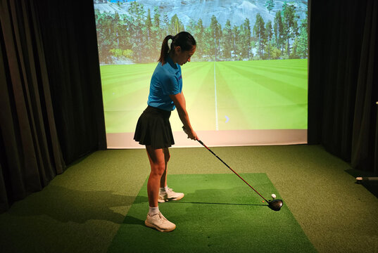Practicing golf swing indoors at a virtual driving range