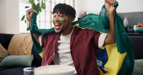 Fototapeta premium Man, flag and celebration in home, soccer and cheering for champion, shouting or winning. Fan, screaming or person in lounge, football or excited for score lead, tournament or supporter in Brazil