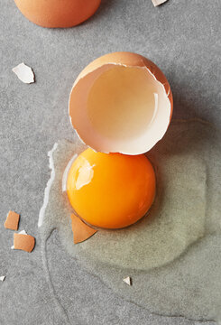 Cracked egg with yolk and shell on grey background
