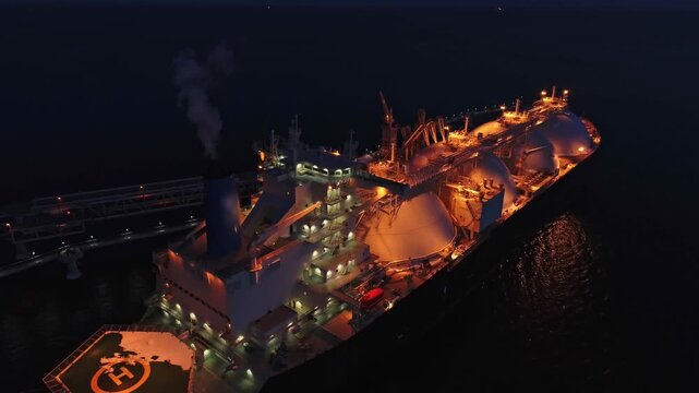 Aerial of Liquified Natural Gas LNG carrier moored to a small gas terminal at night. Fuel crisis. Sanctions