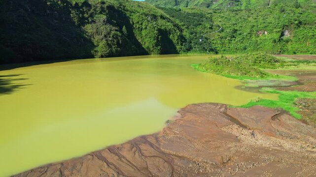 Aerial low drone footage of the Galunggung volcano mountain yellow sulfuric lake, rocky part and forest hills, at early sunrise, in Tasikmalaya regency, Java island, Indonesia