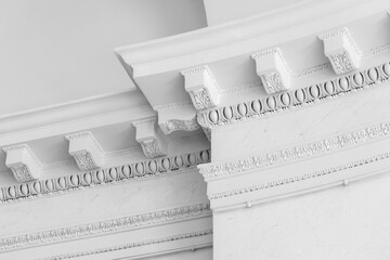 Close-up of an elegant white ceiling cornice corner showing ornate plaster molding, highlighting classical architectural detail and refined interior design © evannovostro