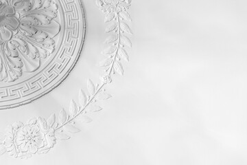 Classic white plaster ceiling medallion with decorative floral molding, showcasing classical relief detail and elegant texture ideal for architecture, interior design, restoration and luxury decor © evannovostro