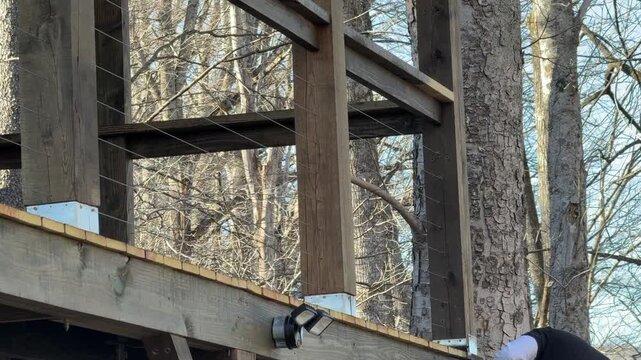 Man staining deck on a ladder