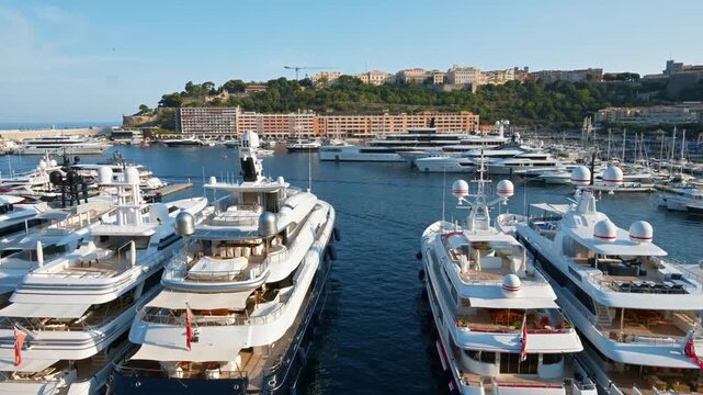 Aerial view of luxury yachts docked in port hercule, monaco with monte carlo cityscape background.