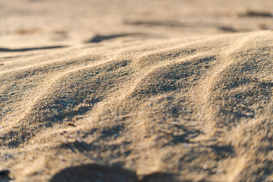 Desert sand texture with wind shaped patterns in warm sunlight natural background