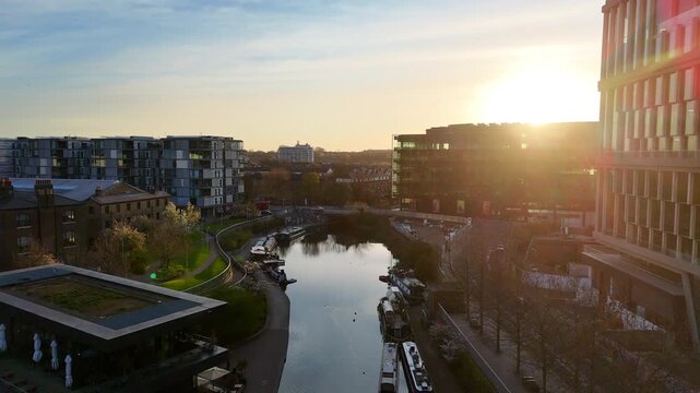 An aerial view of London Regent's Canal at dawn with sunlight rising over office buildings.