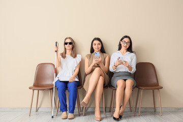 Obraz premium Job applicants with blind woman waiting for interview near beige wall