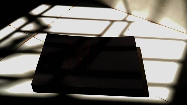 Black Book with Dramatic Shadows on Floor, Minimalist Light and Shadow Concept