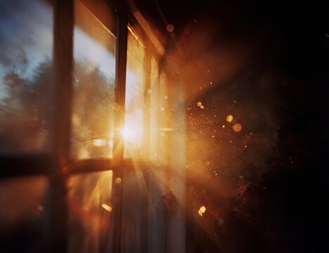 Golden sunlight streams through a dusty window pane, illuminating floating particles