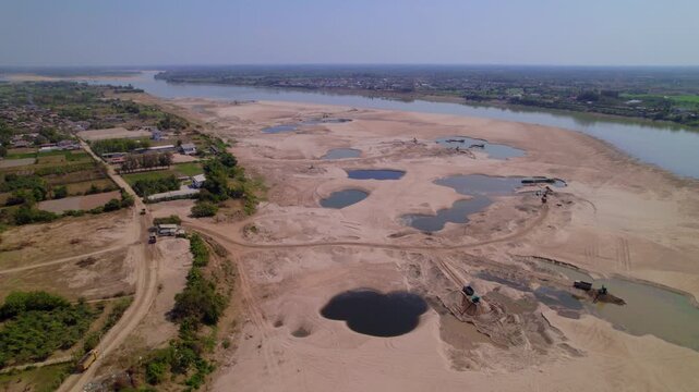 Aerial view of sadny coastline of the Mekong River with construction machinery carrying out demolition.