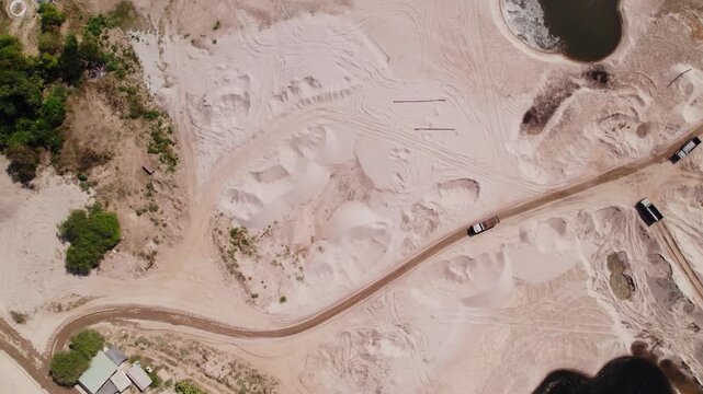 High altitude downward looking aerial view of sadny coastline of the Mekong River with construction machinery carrying out demolition.