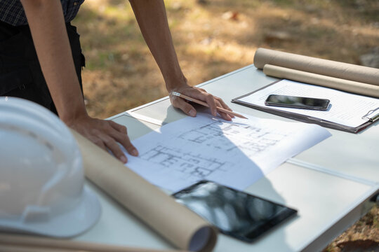 Architect checking blueprint on working table at construction site.