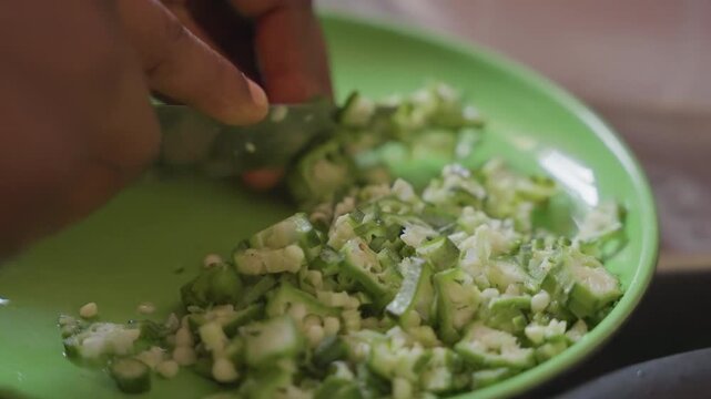 Closeup black hands dicing cucumber on green plate, instructional demo for mindful nutrition, portion control, low calorie salad, careful knife technique, calm pace, wellness focus, bright natural