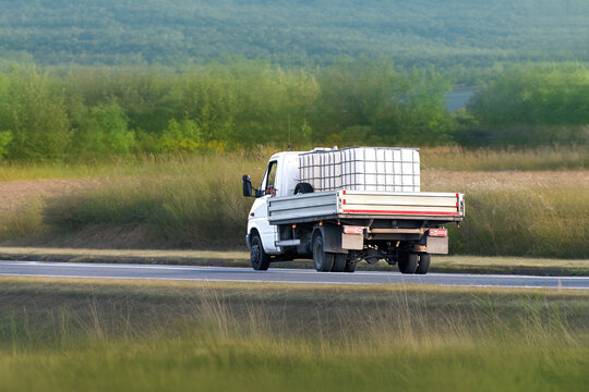 Work truck delivering liquid storage container rurally
