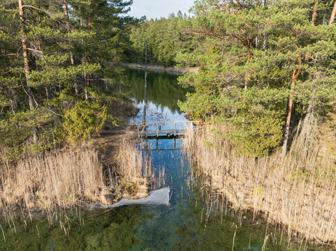 Aerial view of a wooden bridge connecting Green and White lakes in Antu nature reserve with crystal clear turquoise water, Estonia.