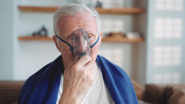 Modern technology in medicine, old man using oxygen machine with nebulizer. Senior sick male person inhaling concentrated oxygen from nebulizer, recovery breathing and relive hypoxia after pneumonia