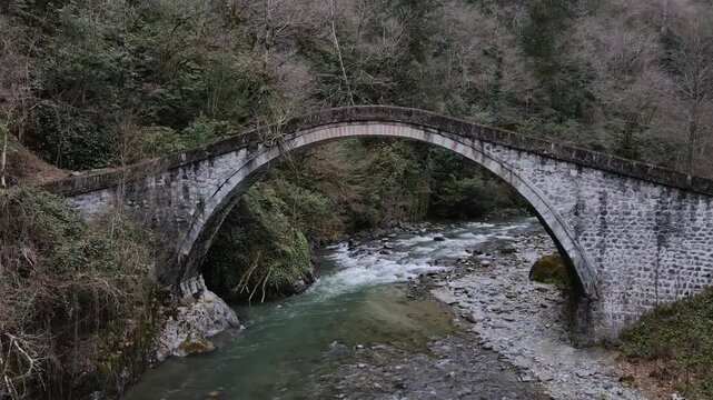Aerial footage of the historical stone arch bridge in the forest.