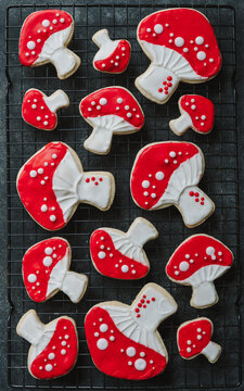 Red and white decorated mushroom cookies on black backdrop.