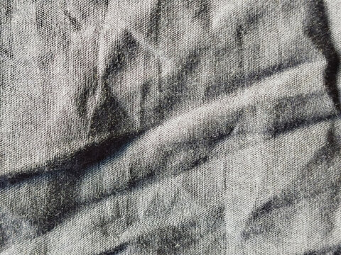 Primer plano de textura de tela vaquera arrugada en color gris con pliegues naturales y sombras marcadas