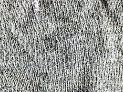 Primer plano de textura de tela vaquera desgastada en color gris con marcas de uso y pliegues naturales