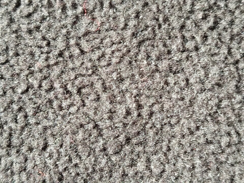 Primer plano de textura de tela boucl&eacute; de color gris oscuro con superficie rugosa y rizada
