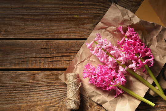 Beautiful pink hyacinth flowers with envelopes and supplies on brown wooden background