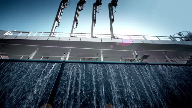 Aerial view of LNG carrier terminal with cargo ship at dock, water pouring down
