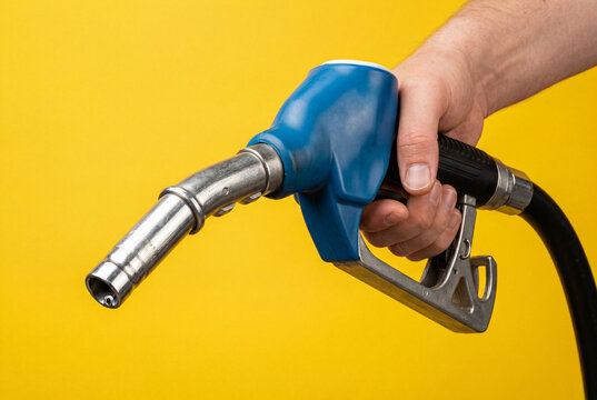 Male hand holding blue gas pump nozzle against yellow background