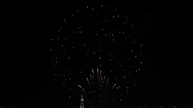 Fireworks explode over city at night, dark sky with festive light