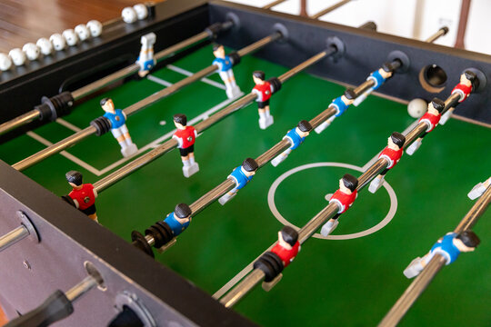 Close-up of a table football (foosball) player figure from the red and blue team, firmly bolted to a shiny metal rod, ready for play.