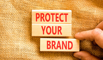 Naklejka na ściany i meble Protect your brand words symbol. Concept words Protect your brand on beautiful wooden blocks. Beautiful canvas background. Businessman hand. Business and protect your brand concept. Copy space.