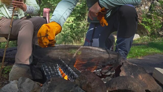 Young couple grilling sausages and burgers over campfire in sunny forest. Authentic outdoor culinary experience, sustainable living and mental wellness in a Finnish national park.