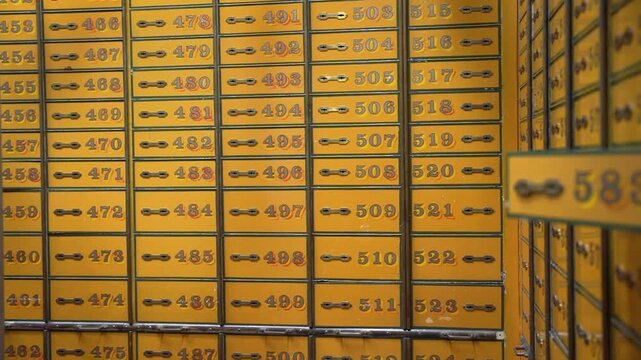 Rows of vintage yellow safe deposit boxes in old bank vault. Close-up of numbered metal lockers for securing valuables and money in a secret treasury.