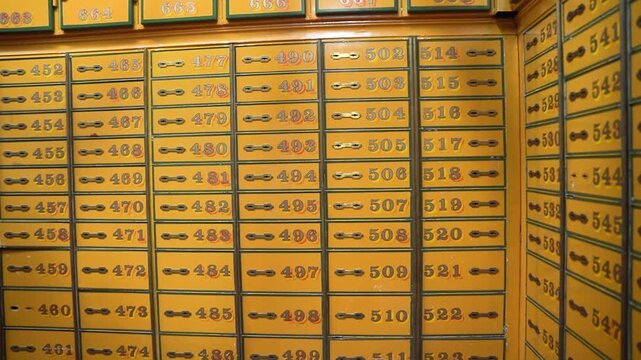Rows of vintage yellow safe deposit boxes in old bank vault. Close-up of numbered metal lockers for securing valuables and money in a secret treasury.