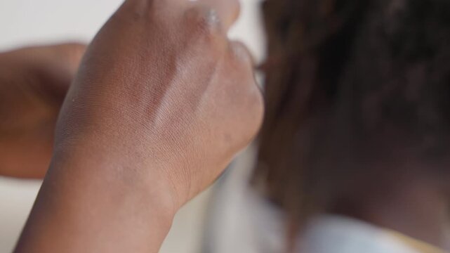 Closeup black hands combing braided hair, mother gently finishing small braids with yellow comb, indoor neutral background, textured afro hair, nurturing domestic moment focused on hands and scalp