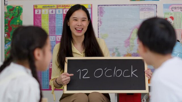 Teacher Instructs Asian Children on Telling Time in Classroom