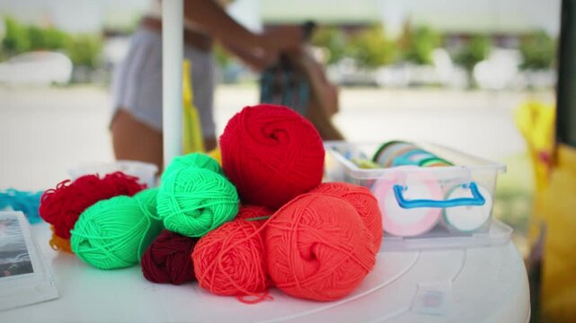 Many threads and ribbons lie on the table against the background of a girl whose African braids are weaving