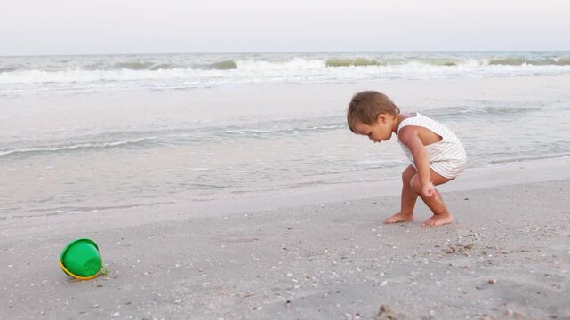 Kid collects shells and pebbles in the sea on a sandy bottom under the summer sun on a vacation