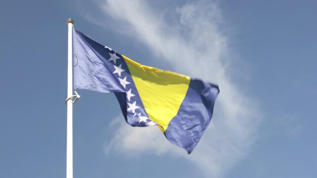 Bosnia and Herzegovina national flag waving against blue sky

