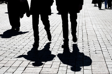 Black silhouettes and shadows of people on the street. Crowd walking down on sidewalk, concept of pedestrians, crime, society, city life