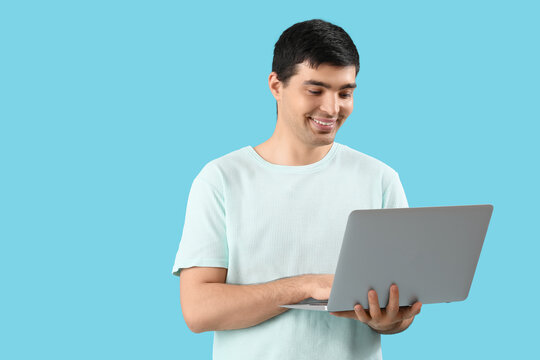 Male programmer working with laptop on blue background