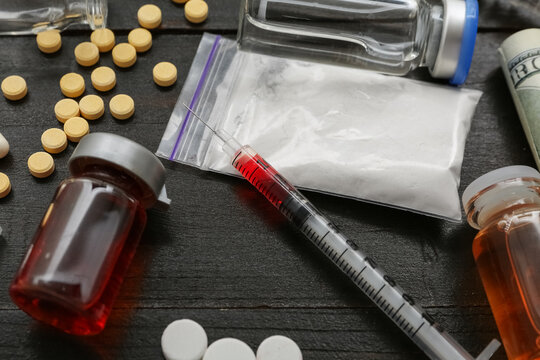 Different drugs and syringe on dark wooden background, closeup
