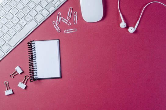 Red and white paper clips, a phone, and an arrow lie on a black desk next to a laptop and office equipment for business communication