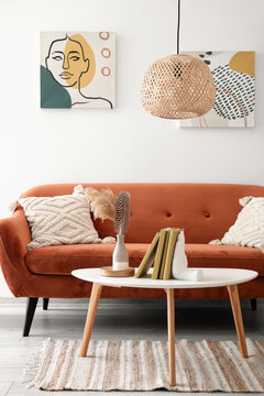 Interior of modern room with sofa and stylish holder for books on table