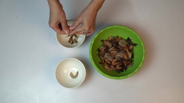 Top View of Hands Peeling Fresh Raw Shrimps into White Bowls