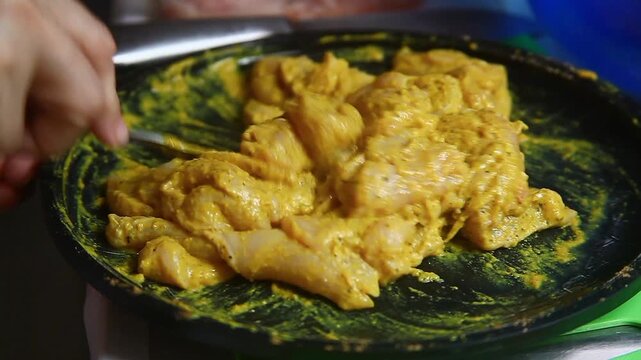 Raw chicken breast being seasoned and prepared for cooking.