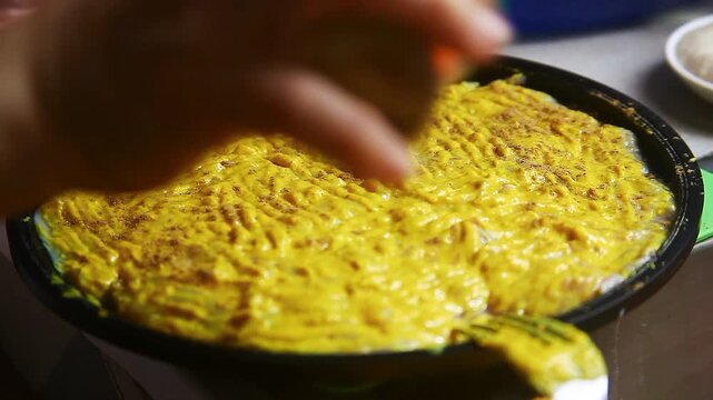 Raw chicken breast being seasoned and prepared for cooking.