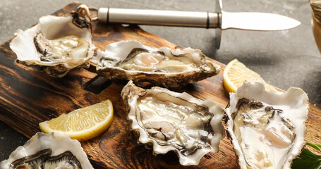 Wooden board with delicious fresh oysters and lemon on dark background, closeup © Pixel-Shot